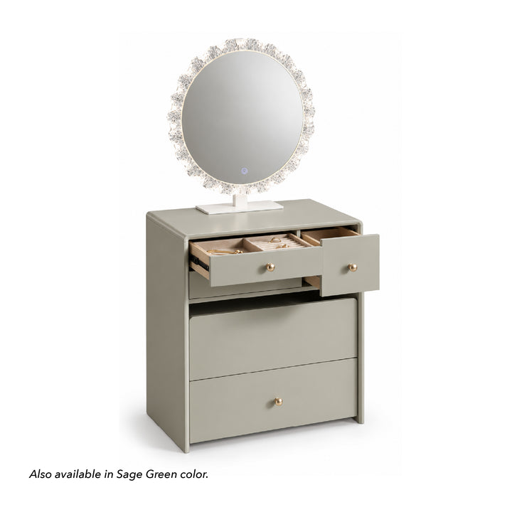 A modern vanity table with an attached oval mirror, shown on a white background. The vanity has a light sage-gray finish, with one drawer open to reveal jewelry compartments.