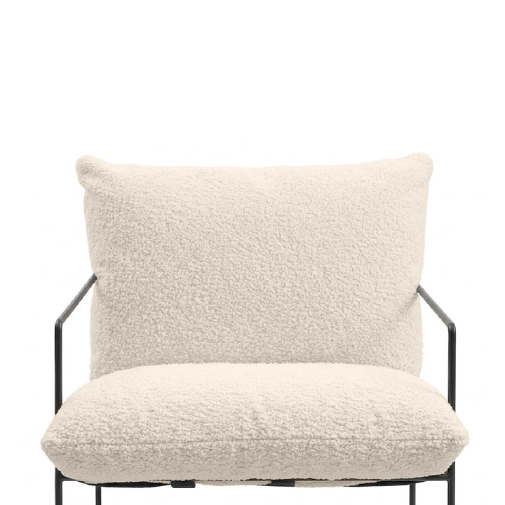 An off-white bouclé upholstered armchair with a black metal frame, shown against a solid white background.