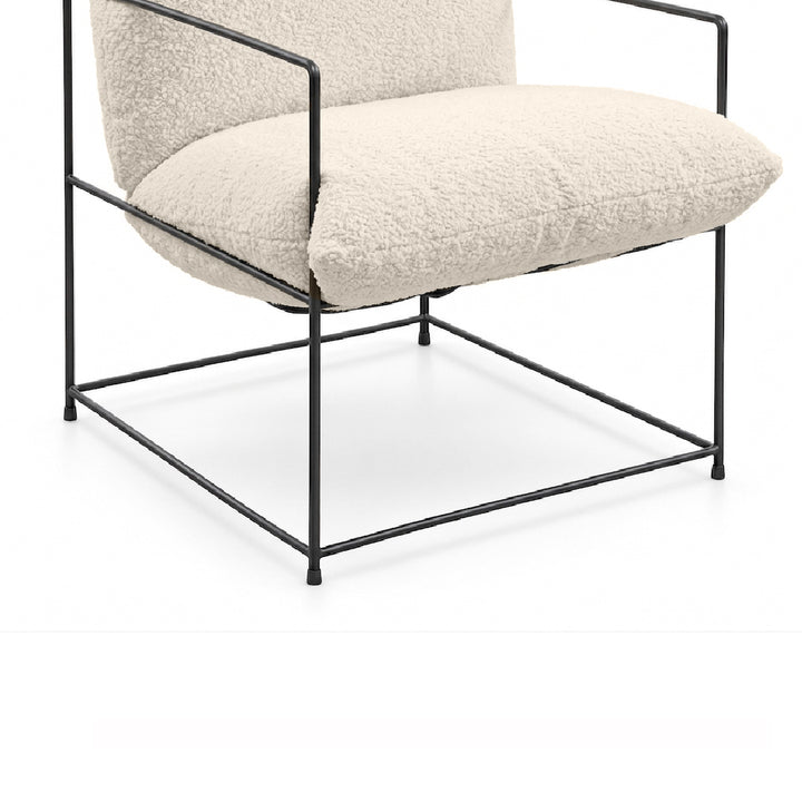 A modern accent chair with a black metal frame and thick, textured cream bouclé cushions, shown against a plain white background.
