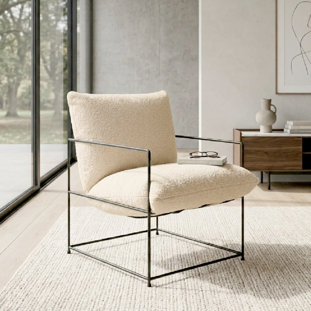 A modern lounge chair with cream bouclé upholstery and a black metal frame, styled in a minimalist living room setting.