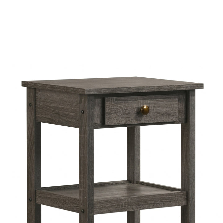 A rustic gray wood end table with a single drawer featuring a round brass knob and a lower open shelf, shown against a plain white background.