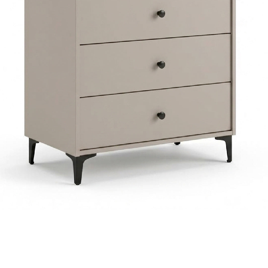 A three-drawer chest of drawers in a light taupe-beige finish with black legs and round black knobs, shown against a plain white background.