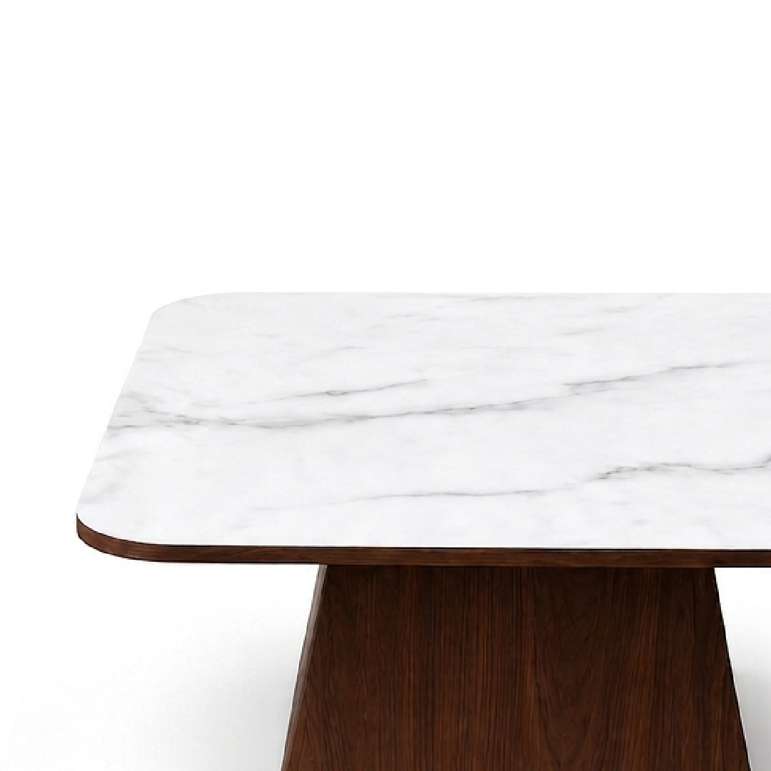 A close-up of a modern table featuring a white marble top with subtle gray veining and a dark brown wooden pedestal base, set against a solid white background.