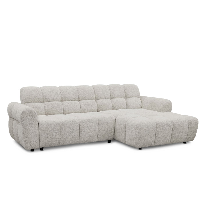 A light grey textured boucle l-shape sofa with a right-facing chaise lounge, featuring a tufted backrest and chunky armrests, shown against a plain white background.
