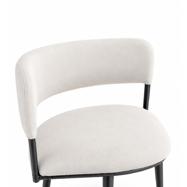 A modern upholstered chair with a curved backrest and seat cushion in a light beige fabric, supported by a black metal frame, shown against a plain white background.