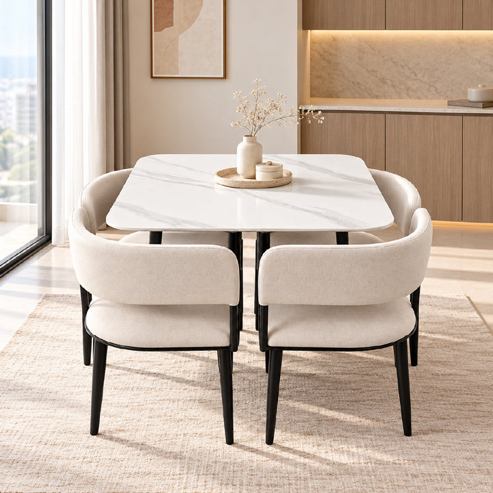A modern dining set featuring a white marble-patterned rectangular table with black legs, surrounded by four upholstered chairs in a warm beige fabric with black legs, set on a textured rug in a contemporary dining room.